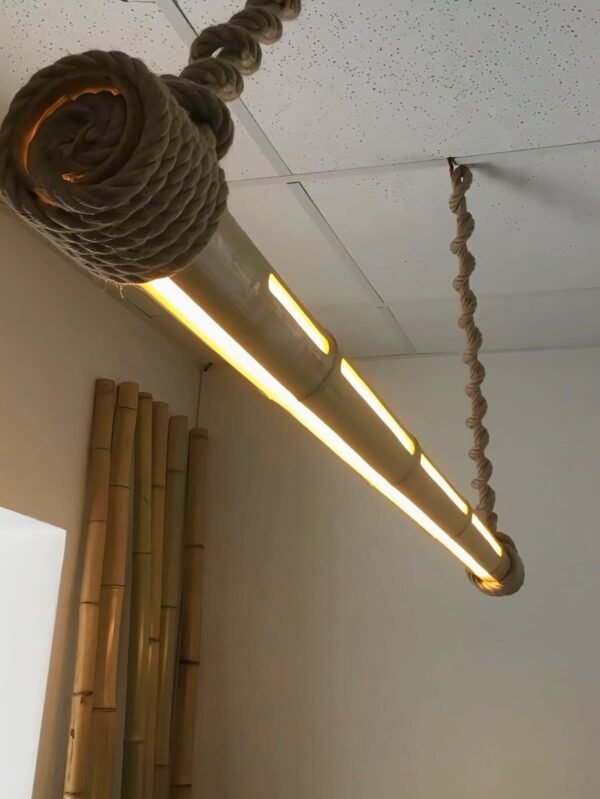 Handcrafted bamboo pendant light with LED illumination, suspended by twisted ropes from a ceiling, creating a warm, cozy ambiance.